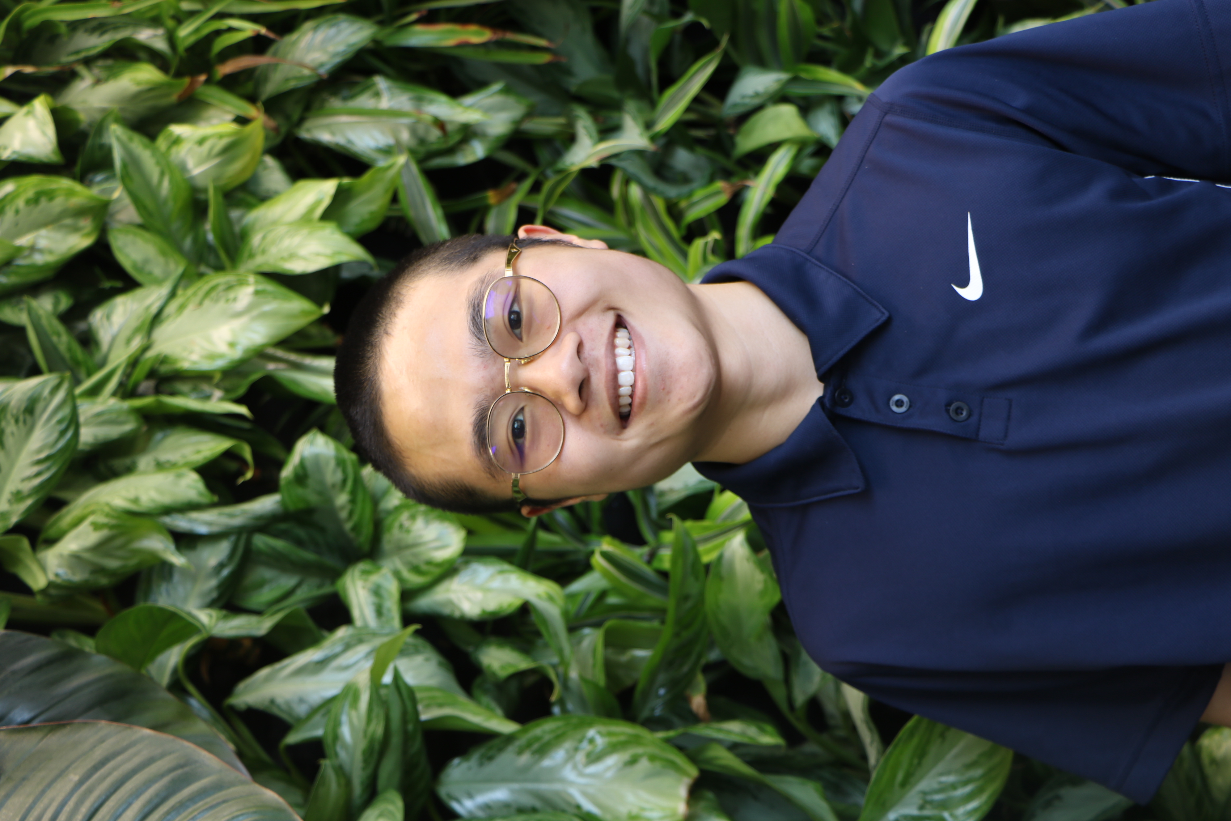 Photo of Theo Ng wearing a navy-blue shirt in front of a greenery wall.